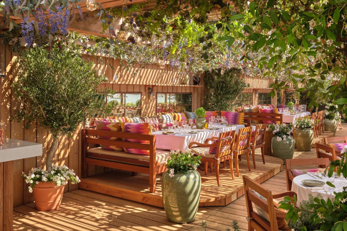Covered terrace dining area with wooden pergola, colorful cushions and set tables
