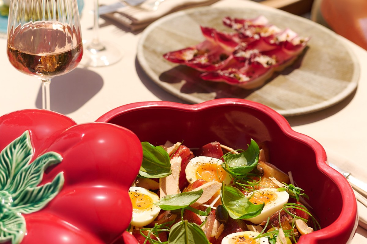 Close-up of tomato dish with egg, basil and carpaccio plate, glass of rosé