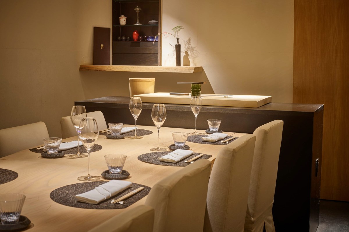 Elegant dining table set with wine glasses, napkins and chopsticks in a warm-lit room.