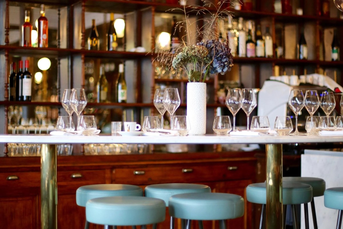 Marble bar table with wine glasses, flowers, and shelves of bottles in the dining room