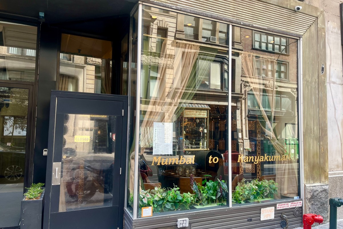 Exterior storefront window of Kanyakumari restaurant in NYC, with 'Mumbai to Kanyakumari' signage and tables visible inside.