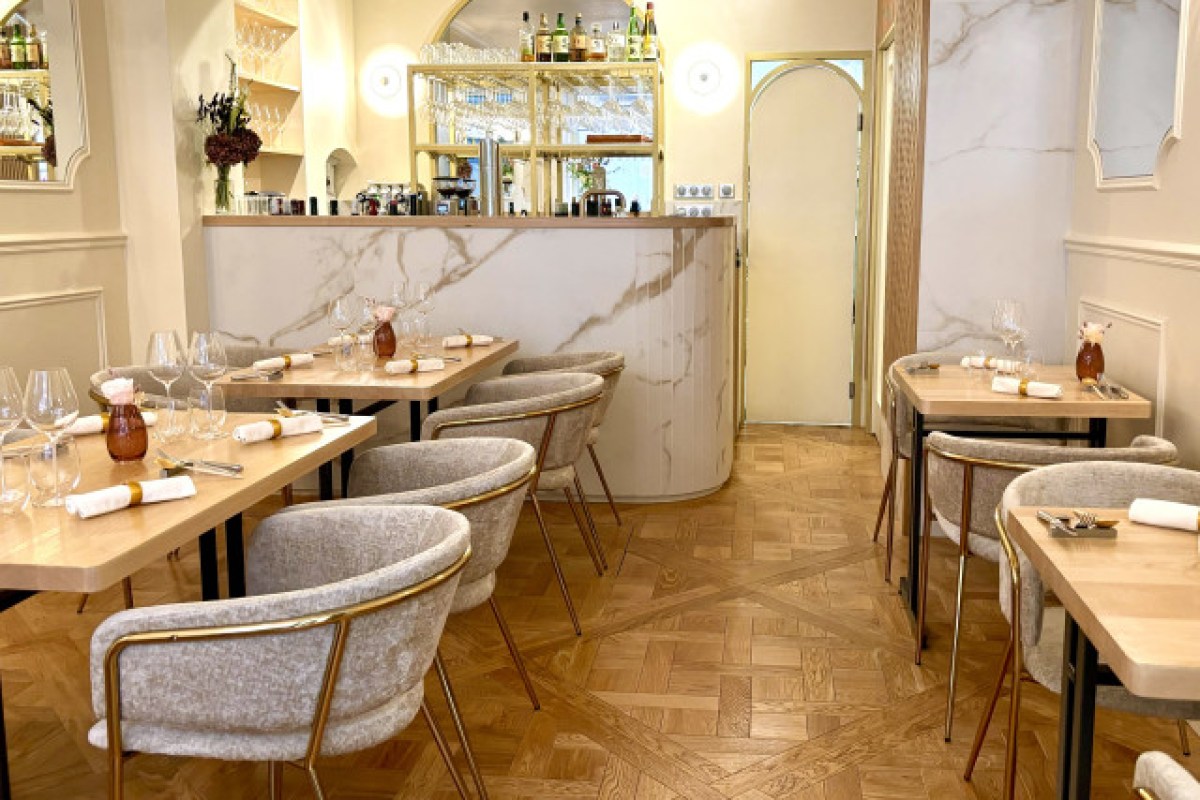 Elegant dining room with marble bar, parquet floor, and tables set with wine glasses and napkins