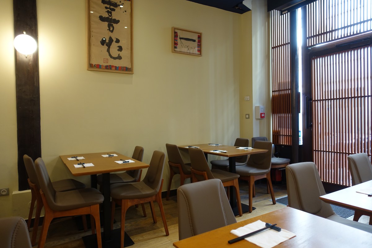 Interior dining room of Kisin with tables, chairs, and Japanese calligraphy art on the wall