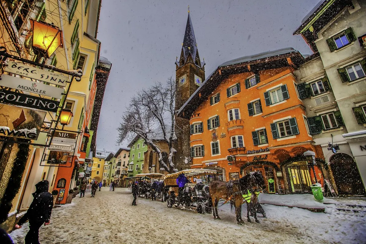Milky Way over Kitzbühel's old town centre with church tower and snowfall
