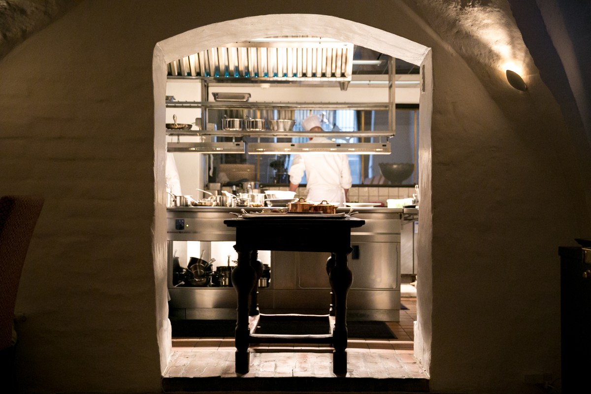 View through a stone archway into the restaurant's kitchen with chefs at work