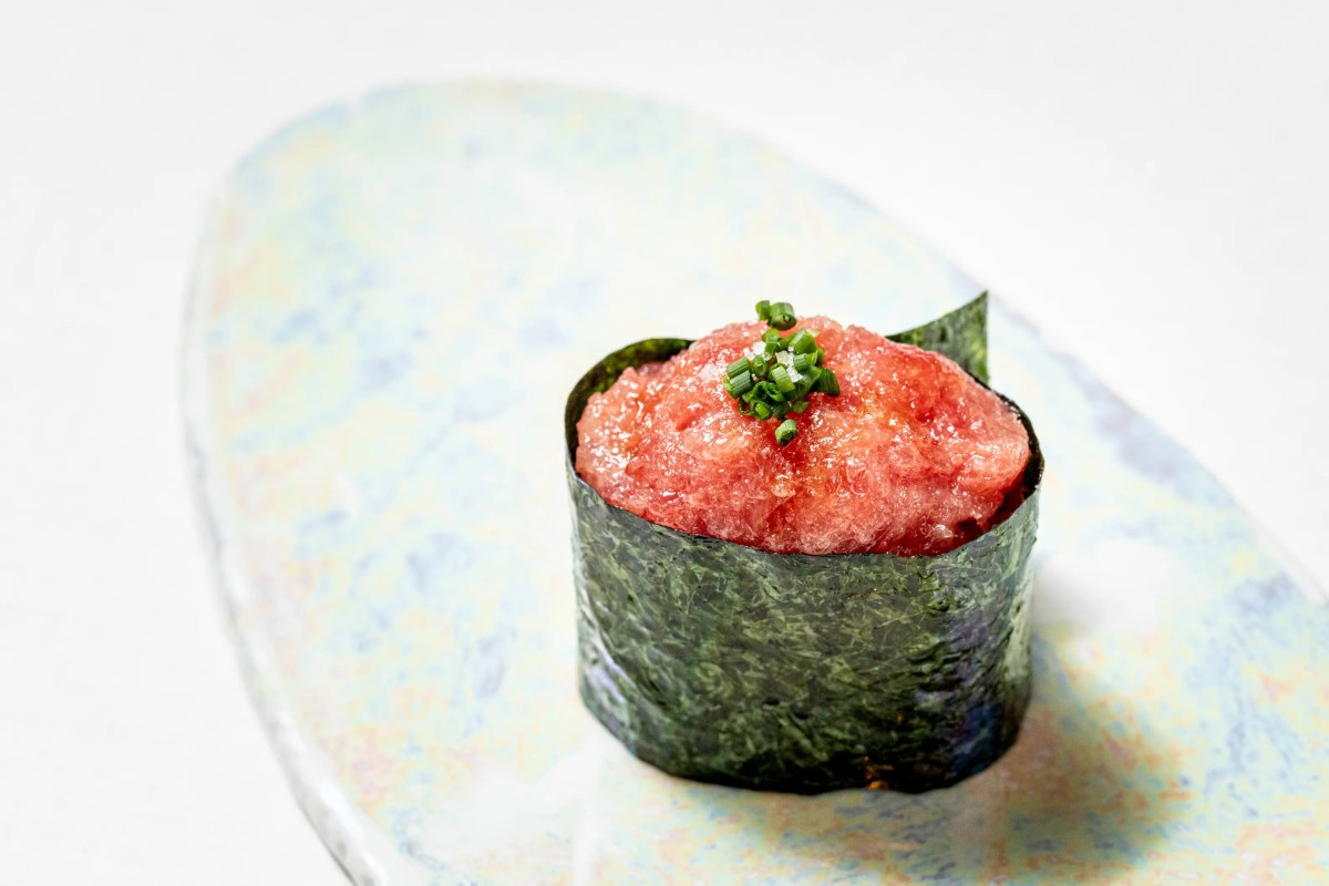 Single gunkan sushi topped with minced tuna and chives on an artistic plate