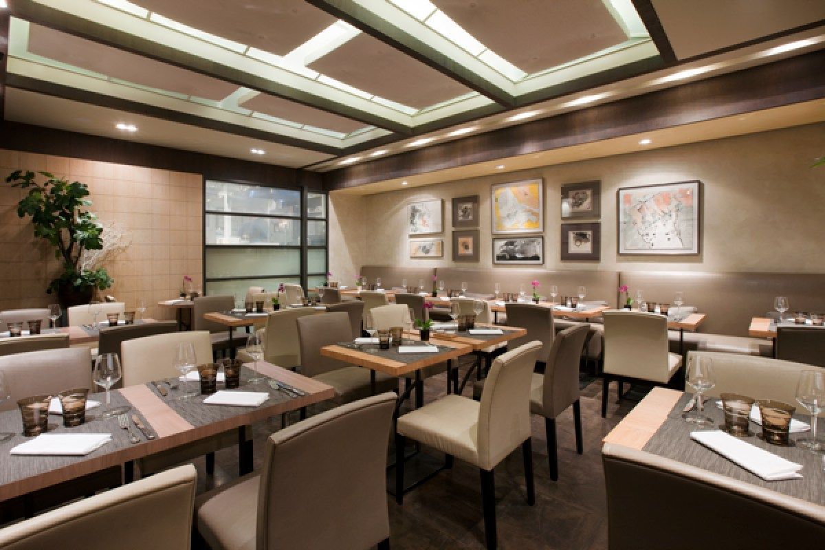 Wide view of restaurant dining room with skylight ceiling, art-covered wall, and multiple set tables