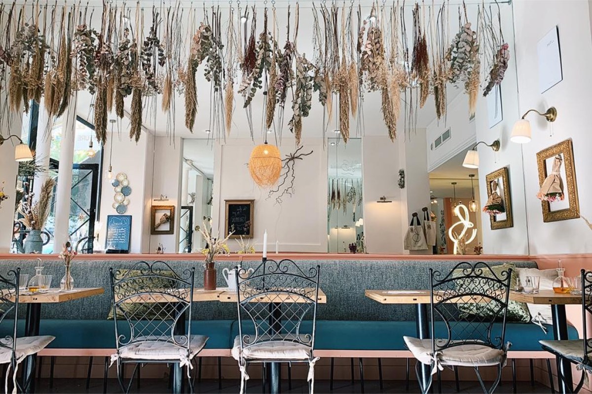 Interior dining room with hanging dried flowers over blue banquette seating and bistro chairs