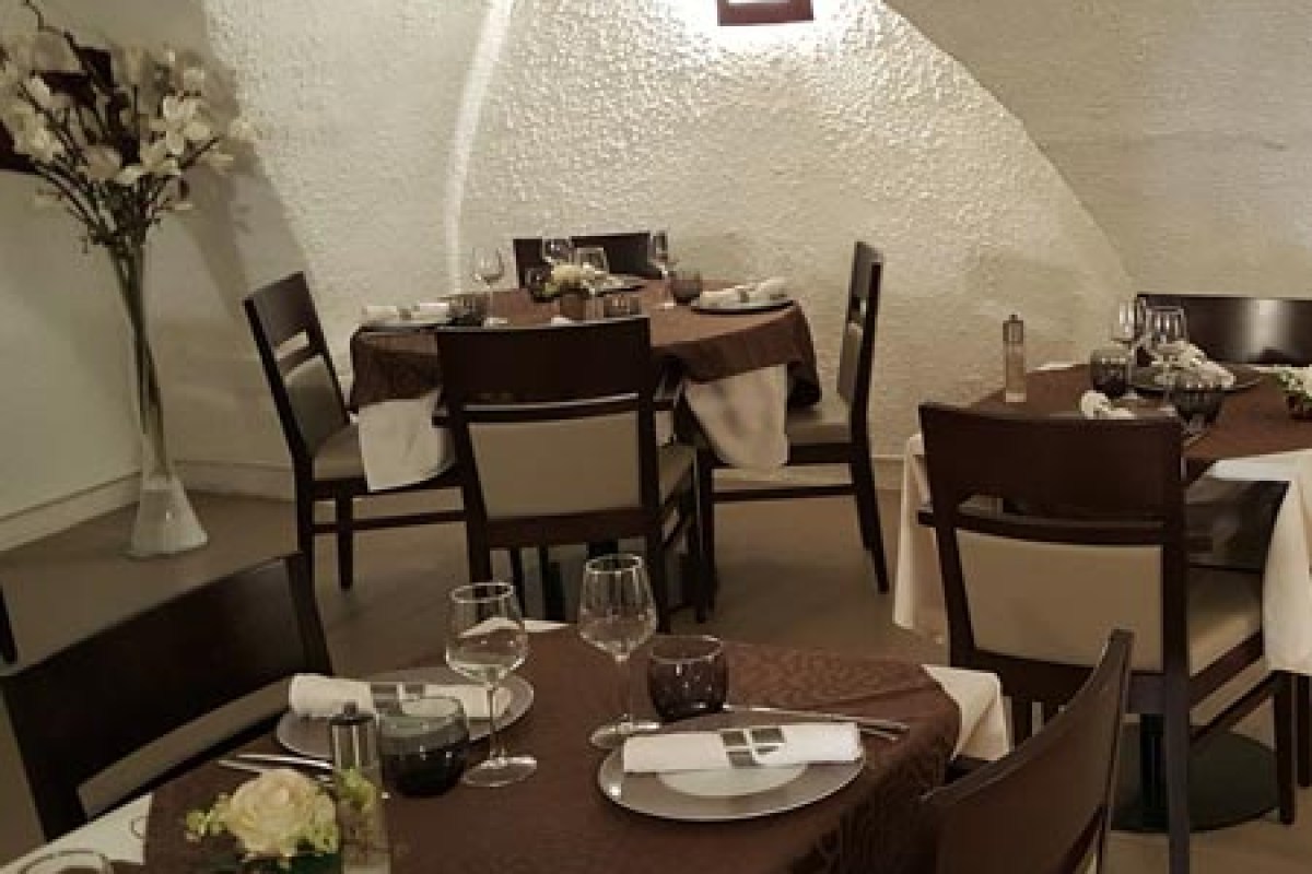 Restaurant dining room with vaulted stone ceiling, tables set with brown tablecloths and wine glasses