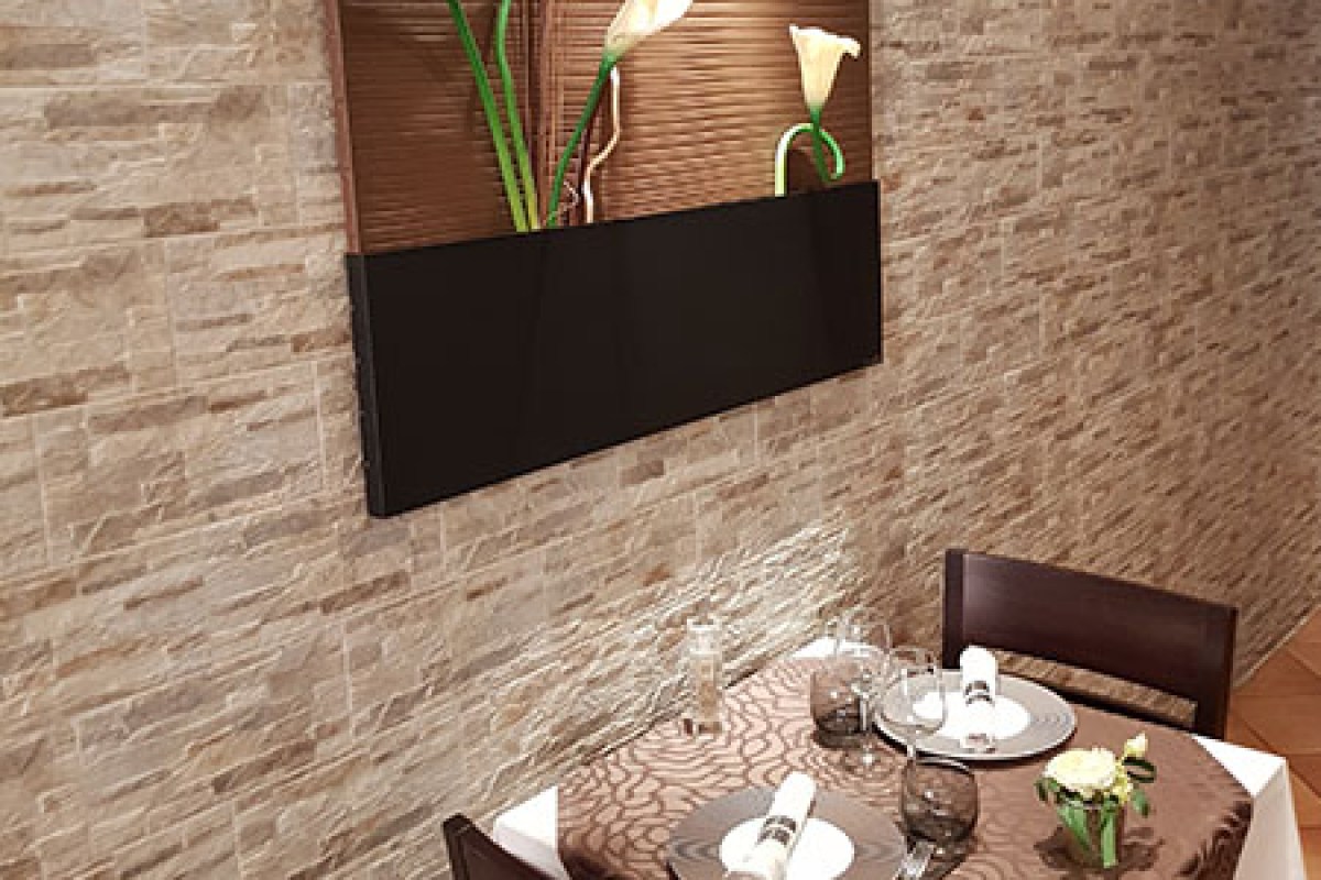 Dining table set with white tablecloth near a stone wall with floral wall art