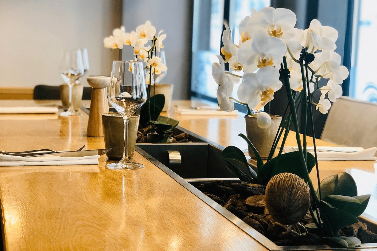 Laid table with wine glasses, cutlery, and white orchid centerpiece at L'Antre Amis
