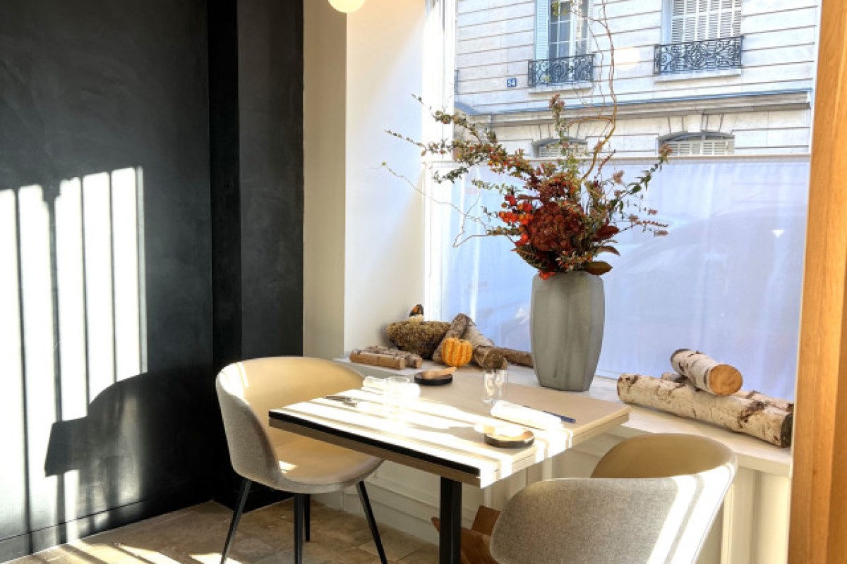 Window table set with cutlery, vase of autumn flowers, logs and pumpkin on sill, Paris street visible outside
