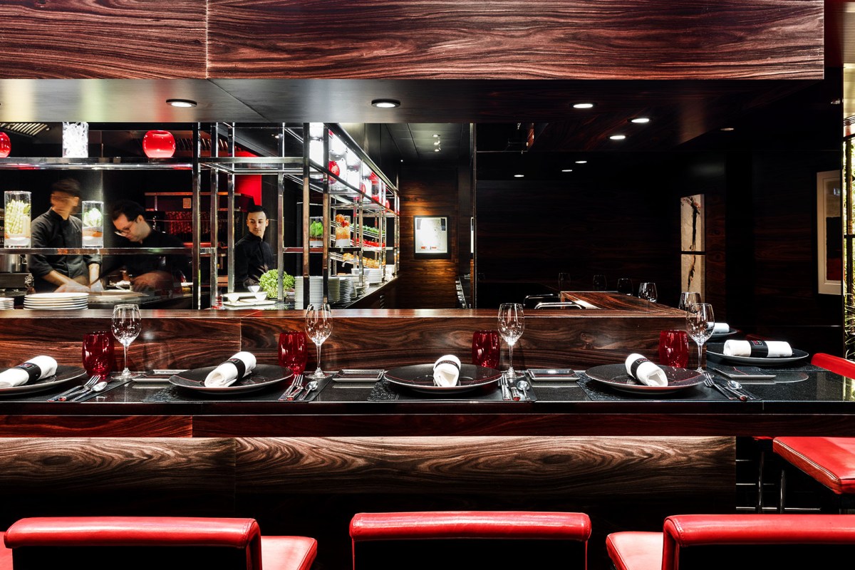 Elegant dining counter with place settings, dark wood paneling, and glimpse into the open kitchen