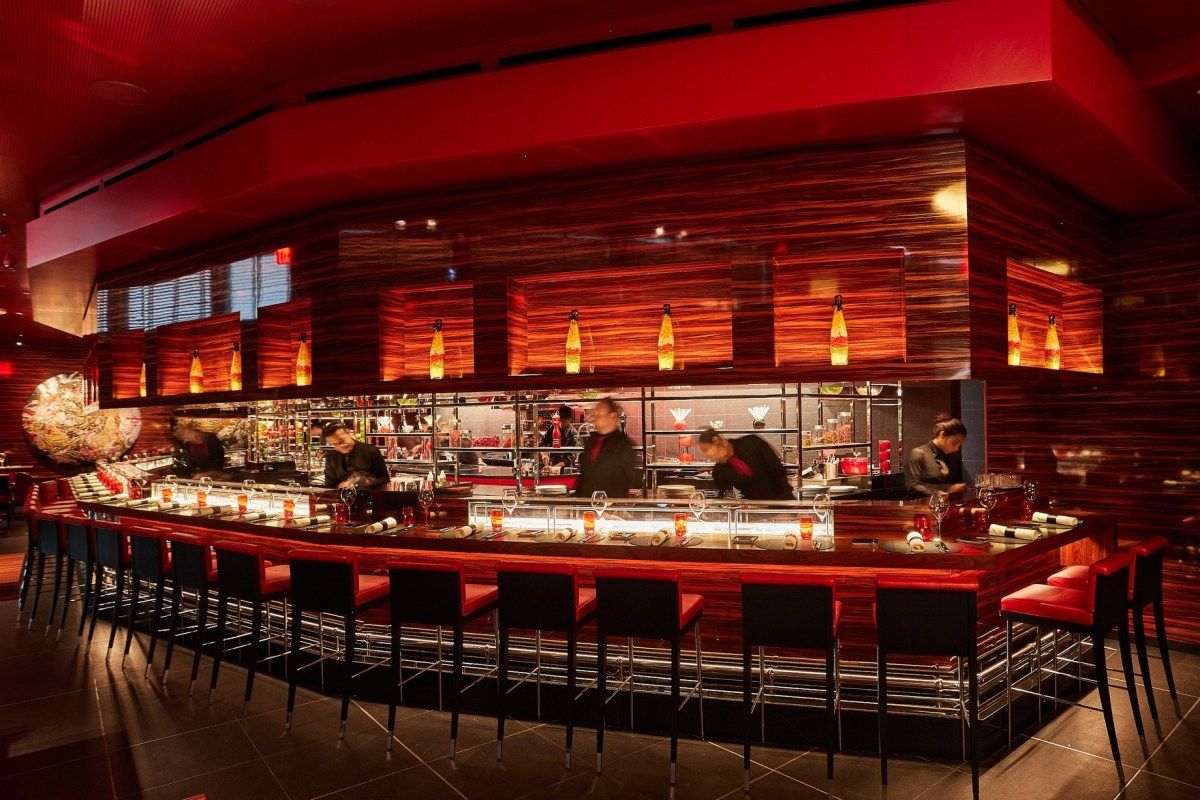 Red-lit interior with long bar counter and open kitchen at L'Atelier de Joël Robuchon Miami