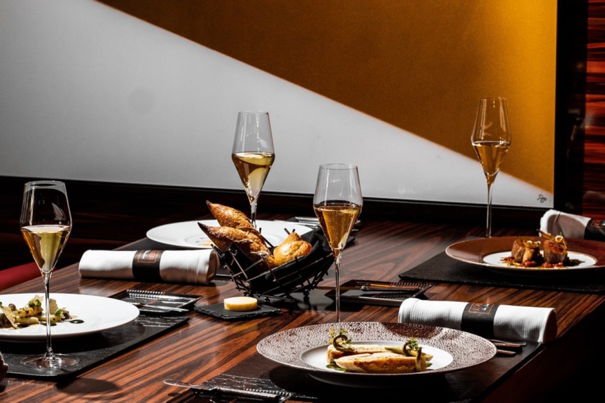 Table set with champagne flutes, bread basket, and plated dishes at the restaurant