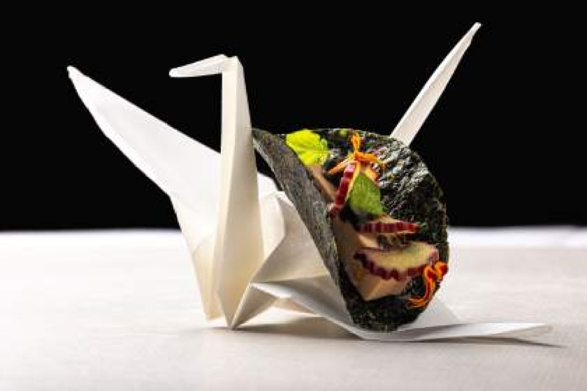 Delicate foie gras dish served inside a nori wrap styled as an origami crane on a white plate.