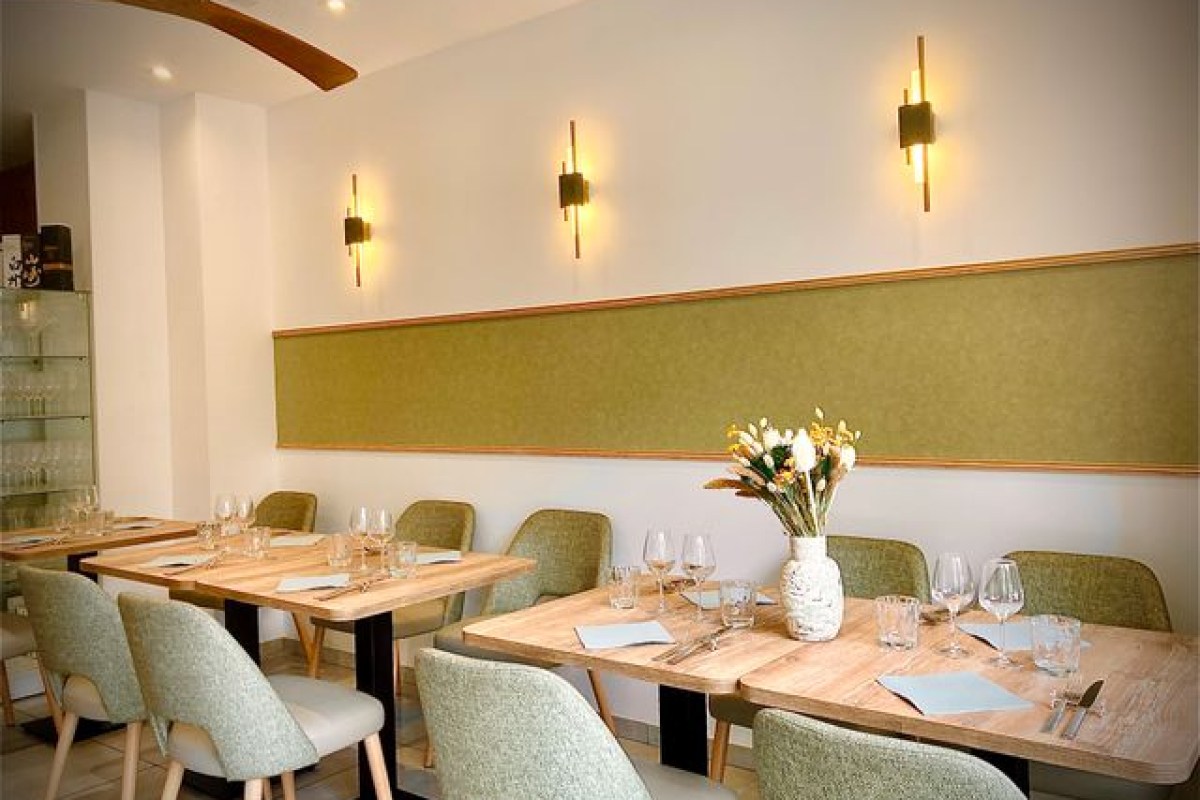 Interior dining room with wooden tables, green chairs, set places and warm lighting
