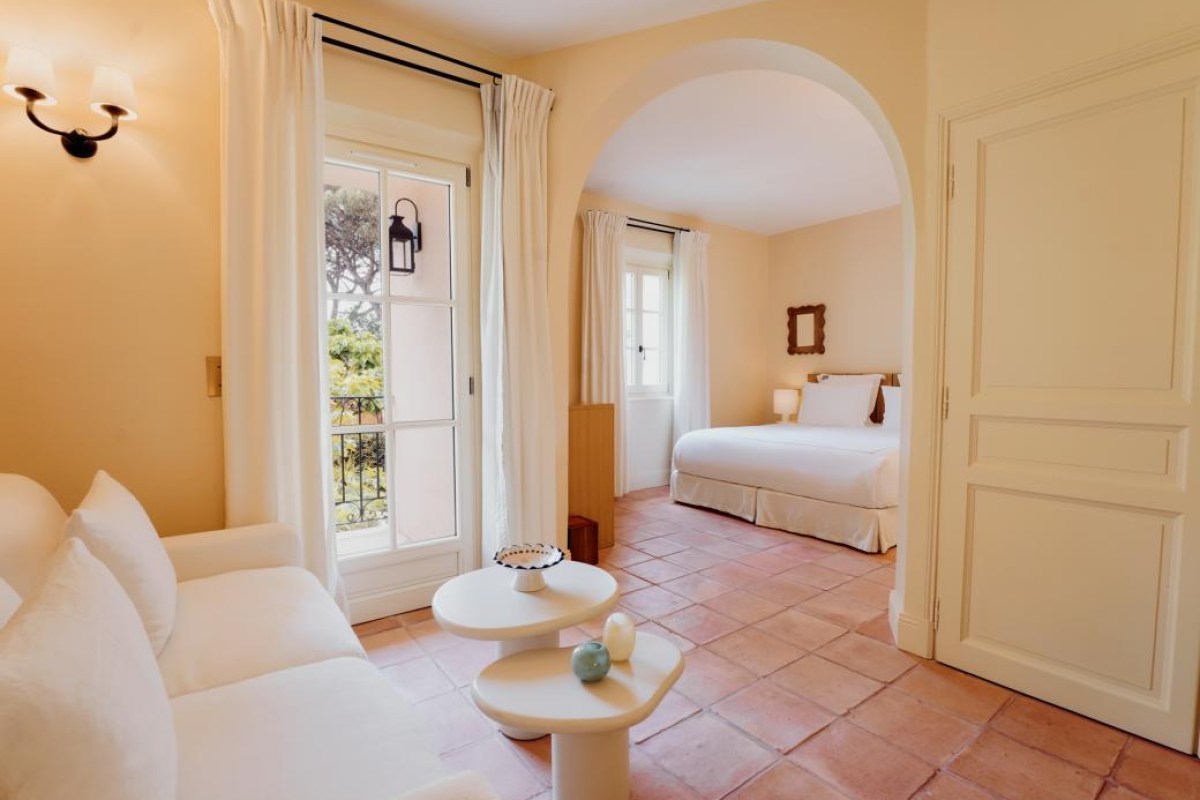 Bright guest suite with living area, archway leading to bedroom with white bed
