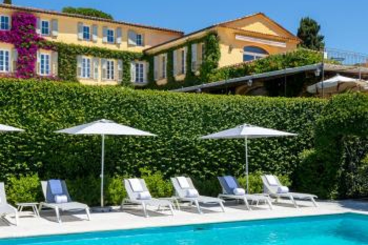 Swimming pool with loungers and umbrellas in front of the flower-covered restaurant building