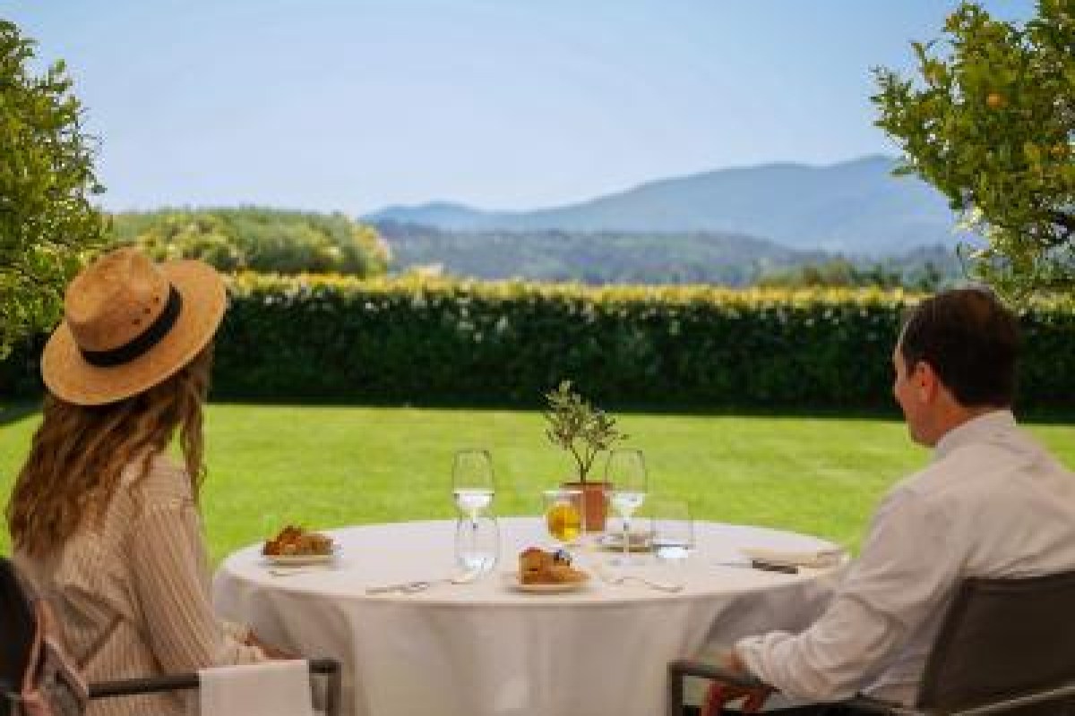Couple dining outdoors on lawn terrace with countryside view