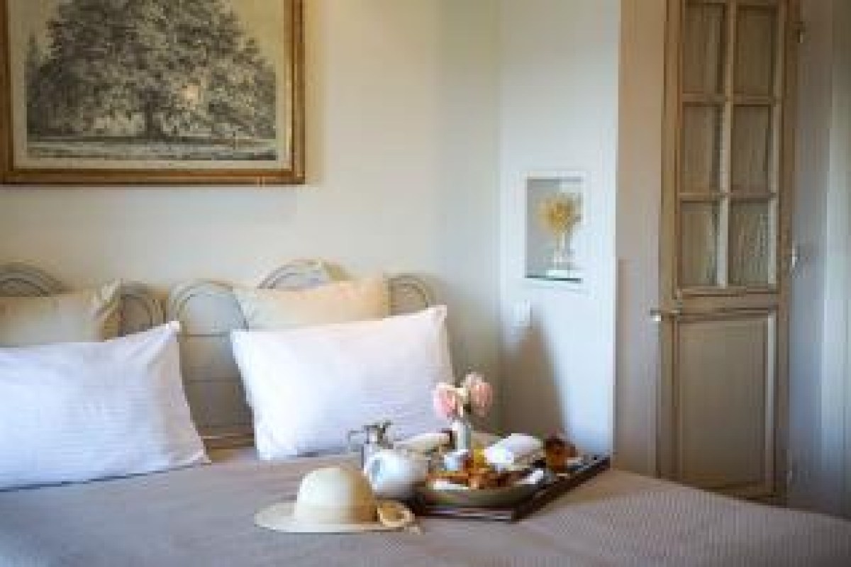 Guest room bed with breakfast tray, straw hat and vintage artwork