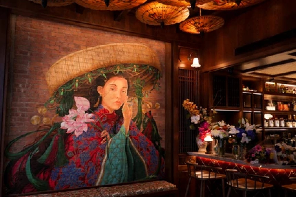Dining room interior with a large painting of a Vietnamese woman and a lit bar area with paper lantern lights