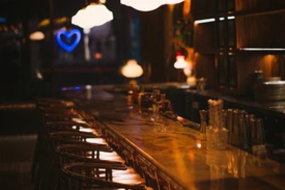 Blurred view of an empty bar counter with warm lighting and bar stools