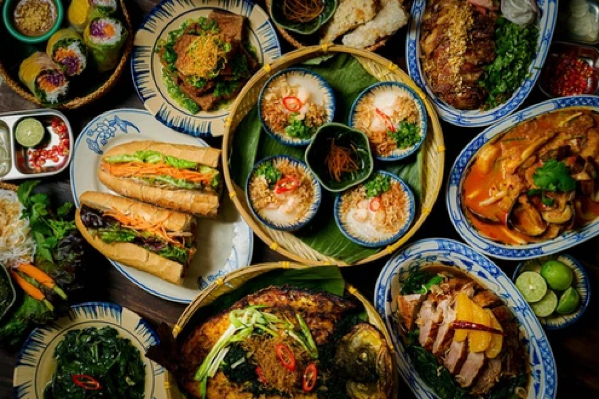 Overhead view of a table filled with assorted Vietnamese dishes, including banh mi, rice bowls, and grilled meats