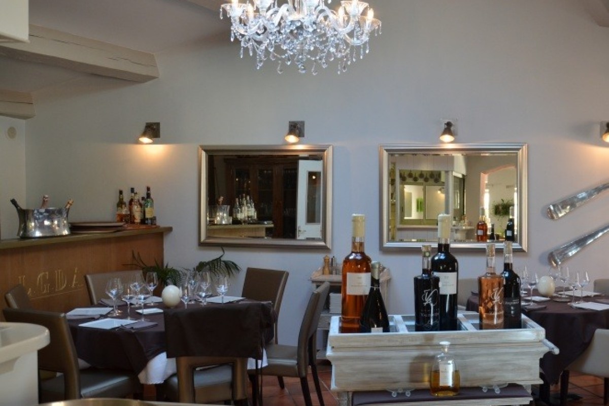 Restaurant dining room with chandelier, mirrors, laid tables and wine bottles on display