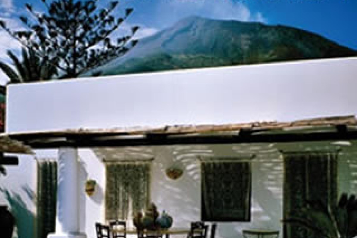 White villa exterior with columns and terrace, mountain in background, slightly blurred vintage-style photo