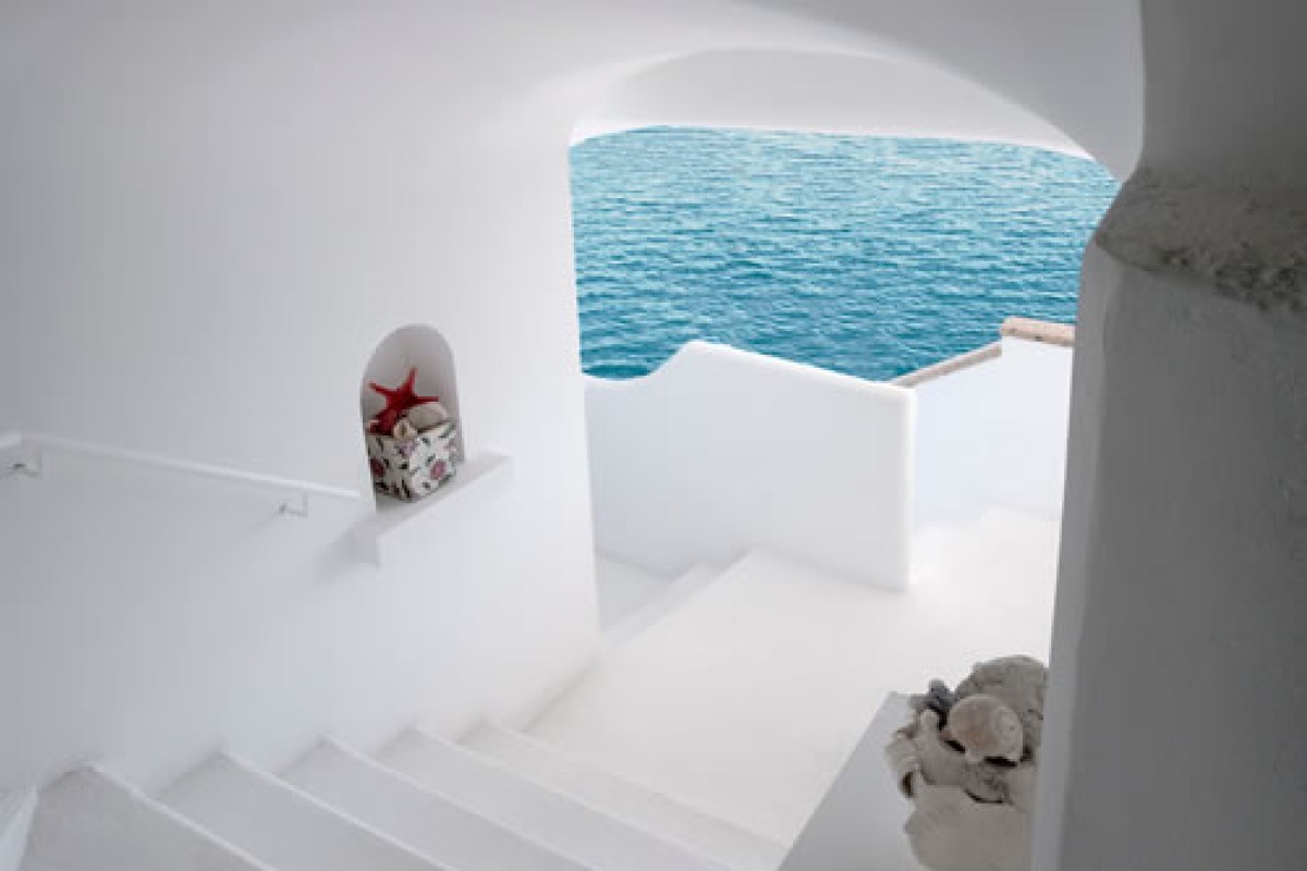 White stairway and archway in a Mediterranean-style interior opening to a sea view terrace
