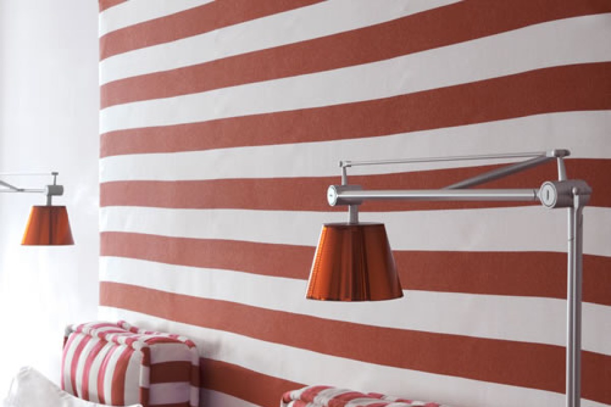 Striped red and white wall with modern swing-arm lamps in a guest room seating area