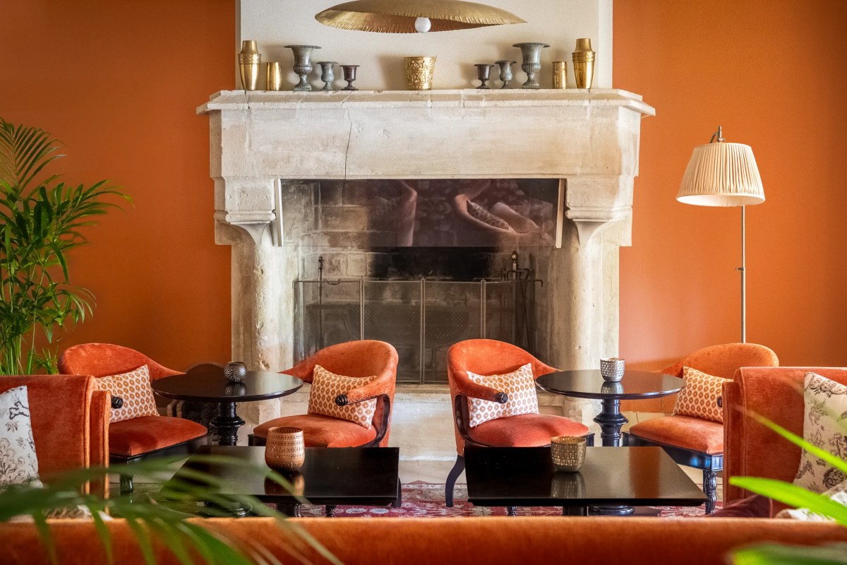 Lounge interior with orange armchairs, stone fireplace mantel, and warm orange walls