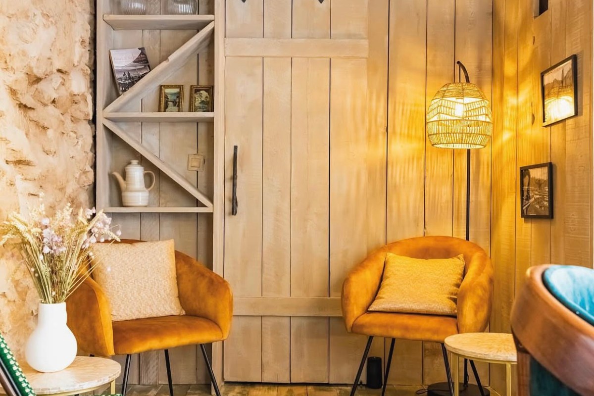 Cozy restaurant corner with mustard velvet armchairs, wooden paneling and warm lighting