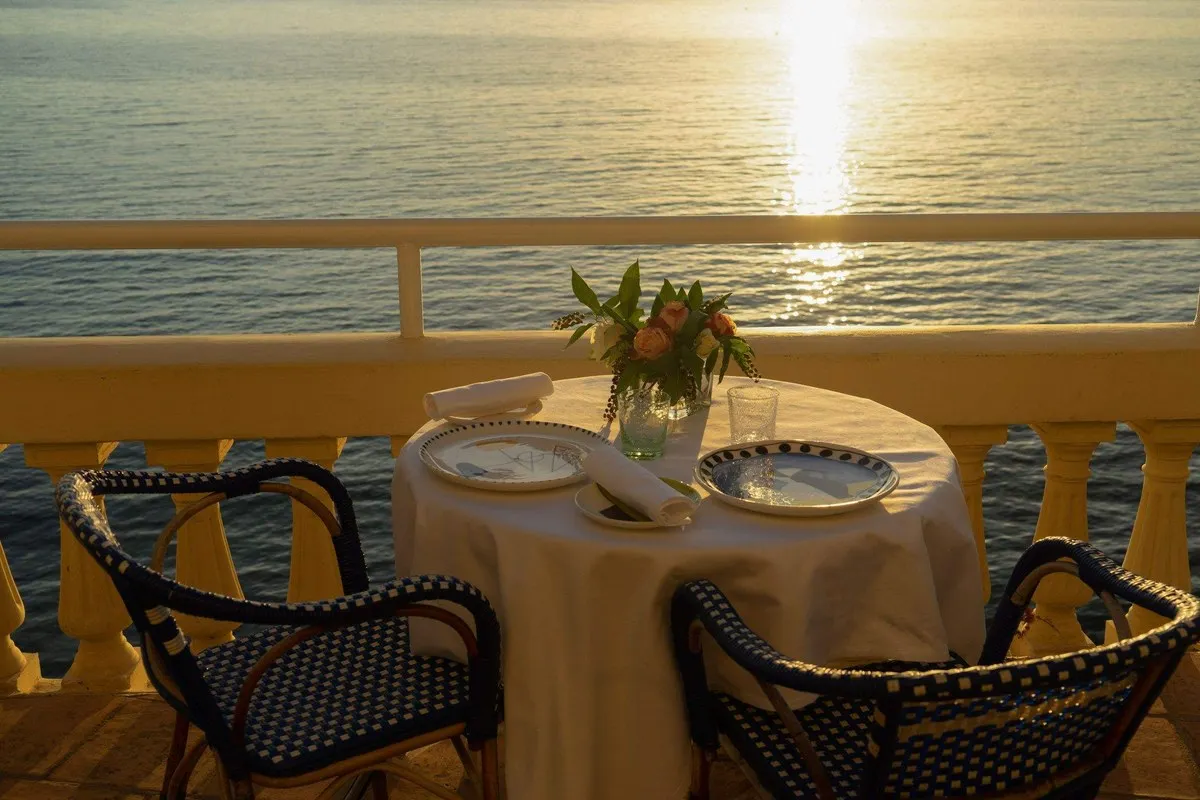 A laid table on the terrace of La Passagère at Hôtel Belles Rives in Juan-les-Pins, with the sea at sunset behind the balustrade