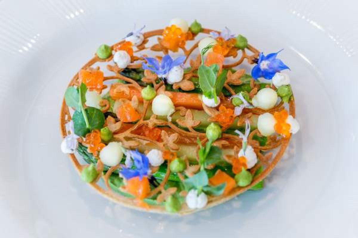 Elegant plated dish with vegetables, caviar, edible flowers and a crisp lattice garnish