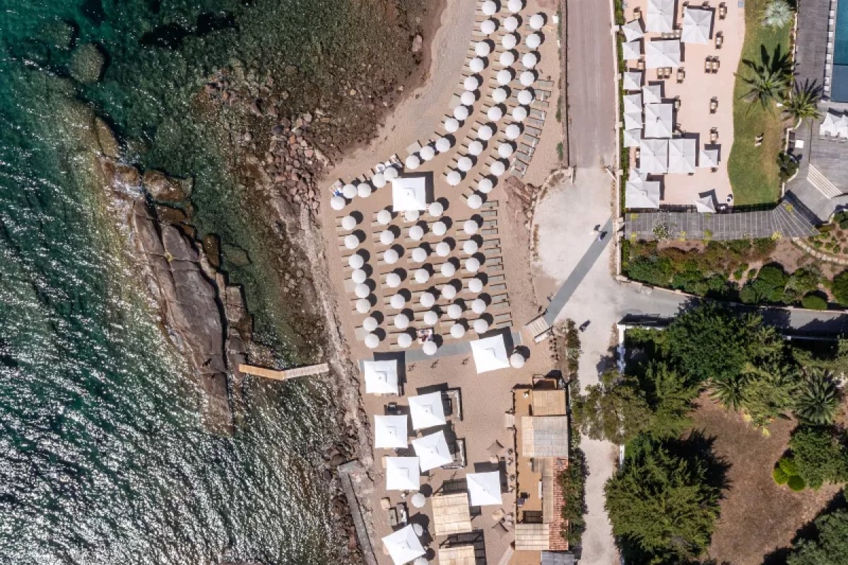 Aerial view of rows of white umbrellas and loungers on hotel beach