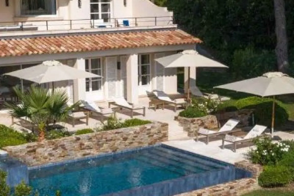 Aerial view of a Provençal-style villa with terracotta roof, pool, sun loungers and umbrellas on a stone terrace