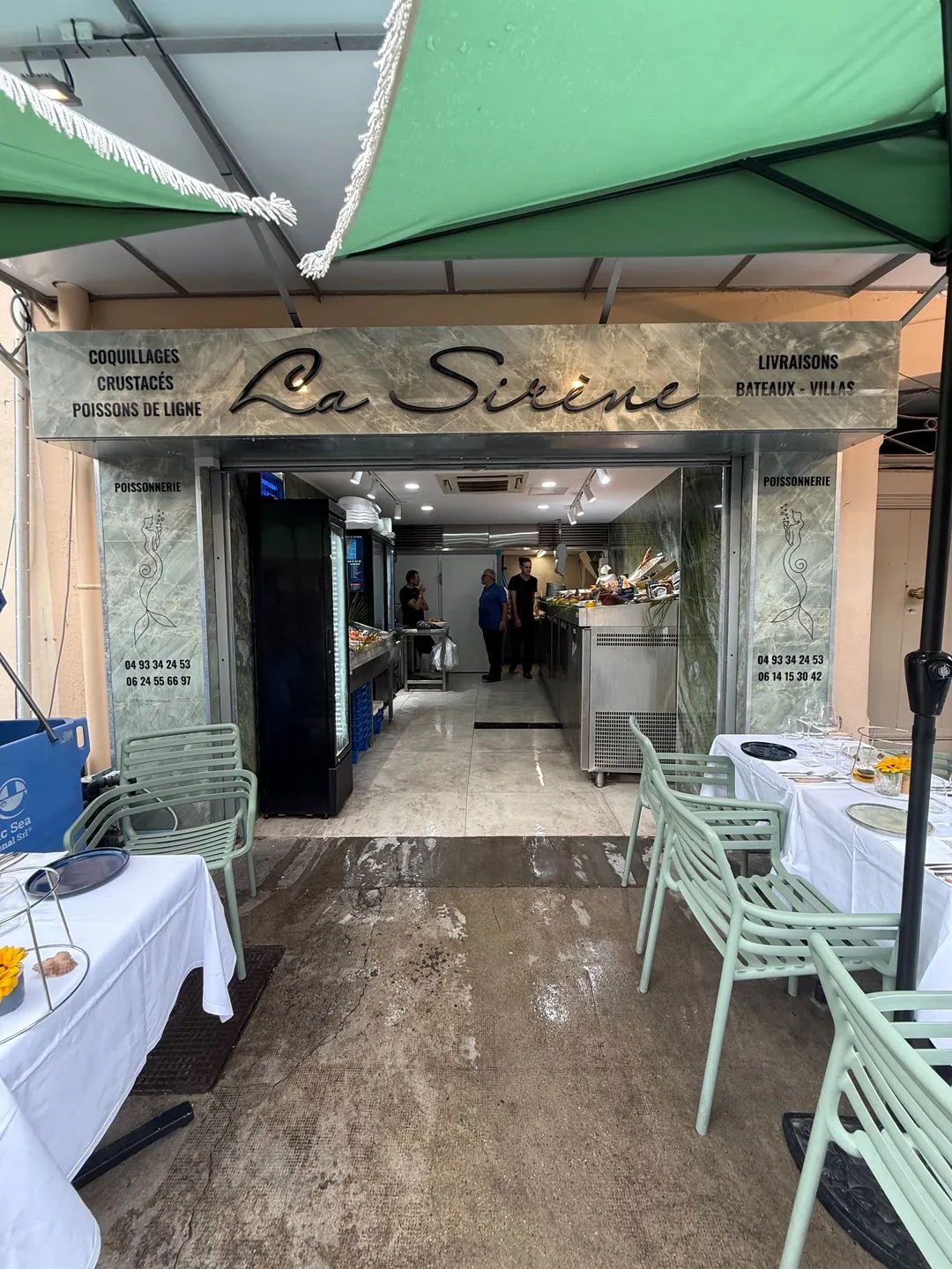 The shopfront of La Sirène on Cours Masséna in Antibes, under a green awning, with sage-green chairs and laid tables outside
