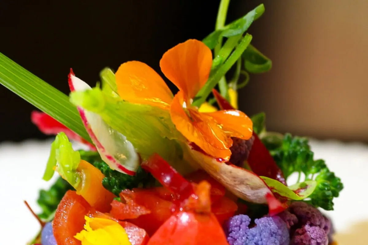 Close-up of a colorful garnished dish with edible flowers, radish, and mixed vegetables