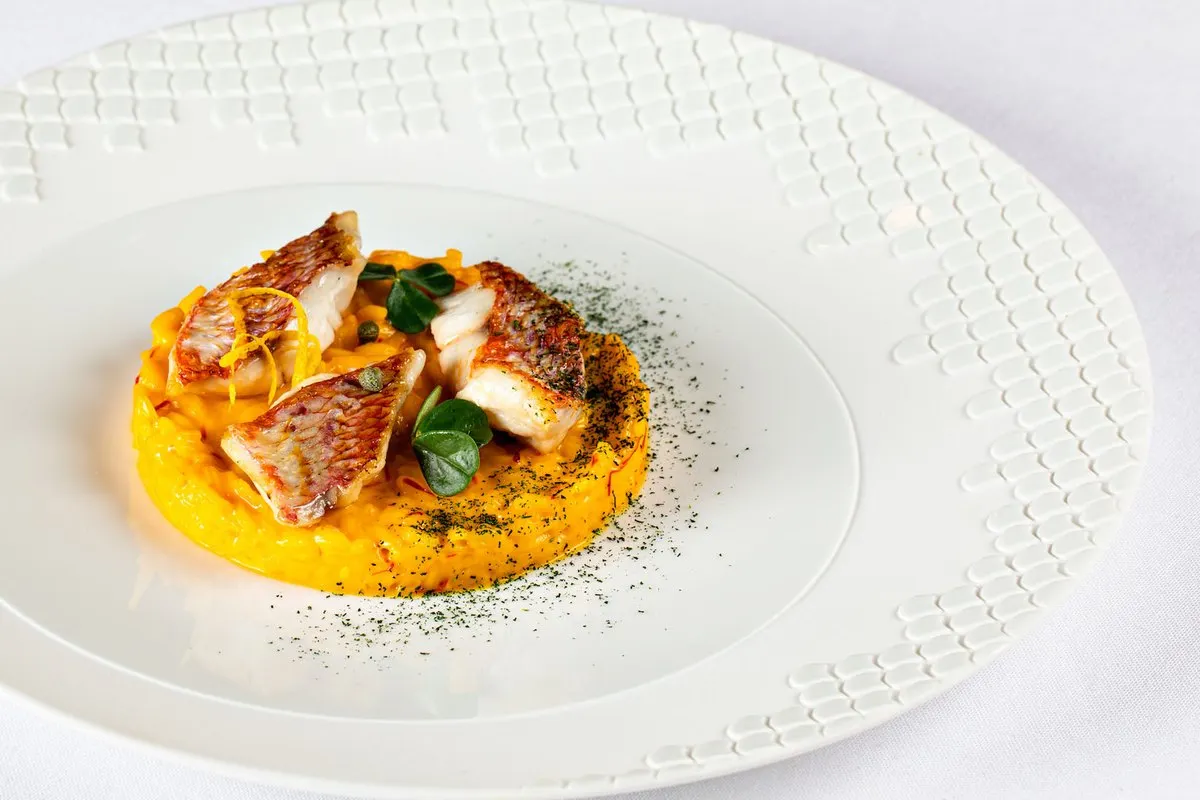 A plate at La Table d'Antonio Salvatore in Monaco: fillets of red mullet on a saffron-yellow base, with herbs, on a white embossed plate