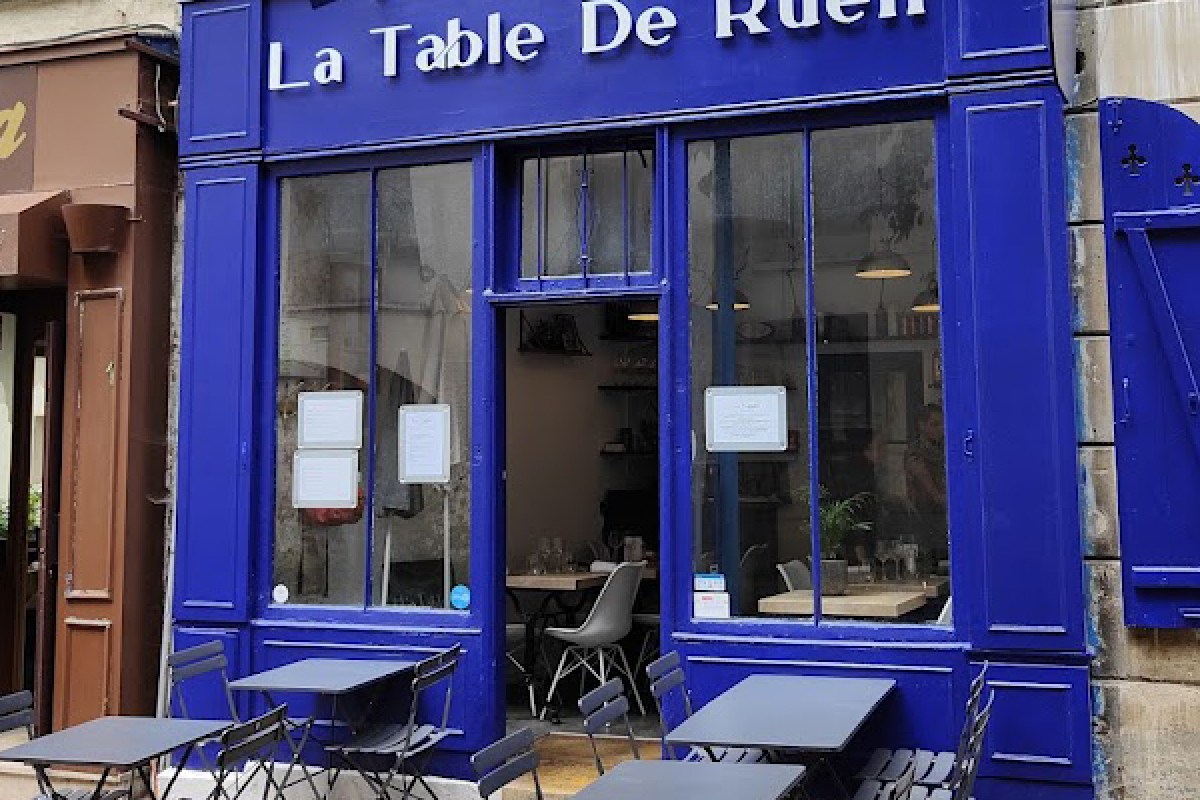 Blue-painted storefront exterior of La Table De Rueil with outdoor terrace tables and chairs