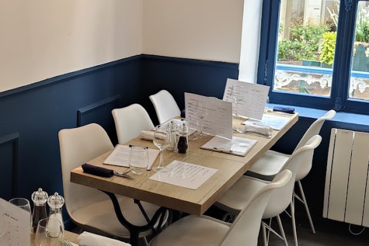Dining room table set with menus, wine glasses and cutlery beside a window