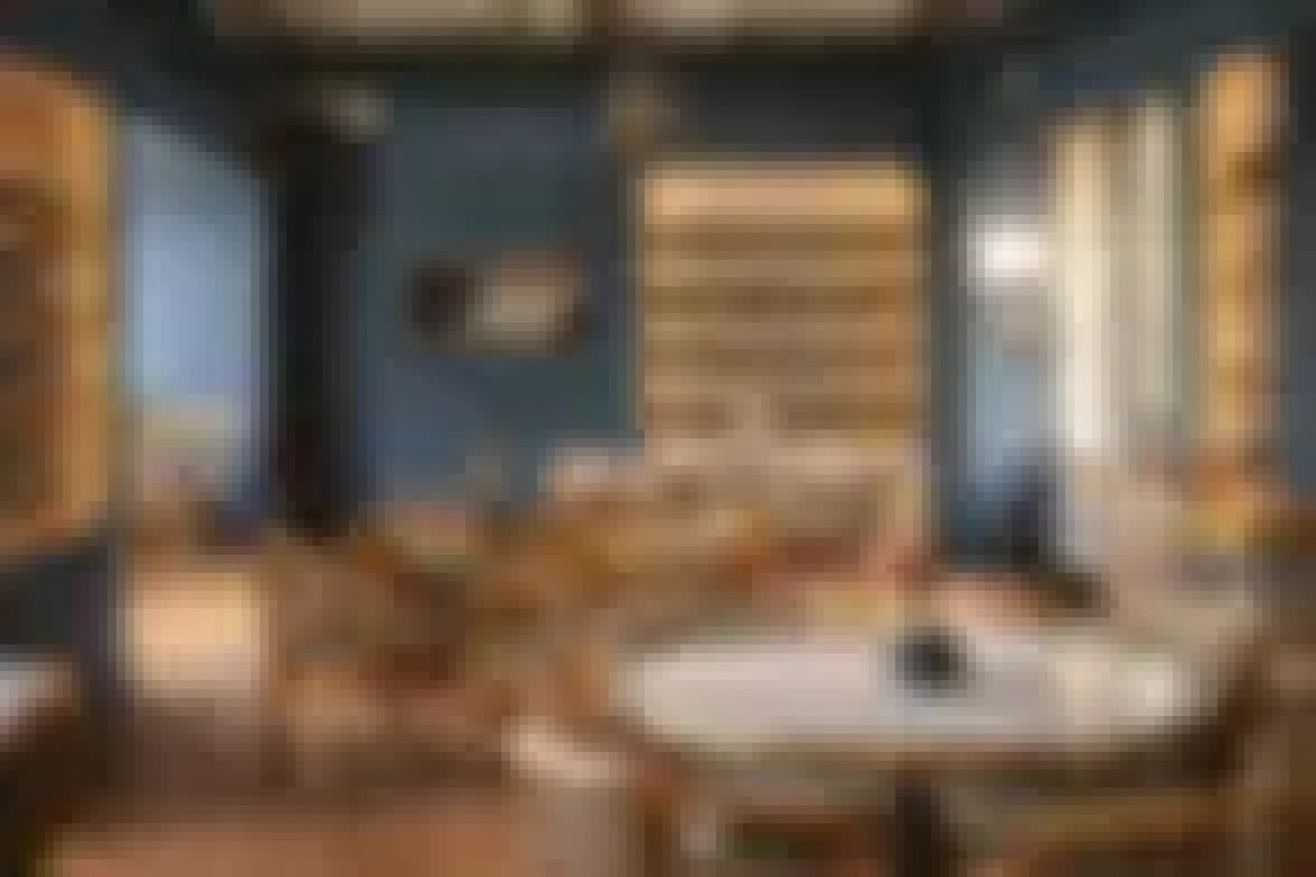 Dining room interior with blue walls, warm wood paneling, a round mirror and table settings