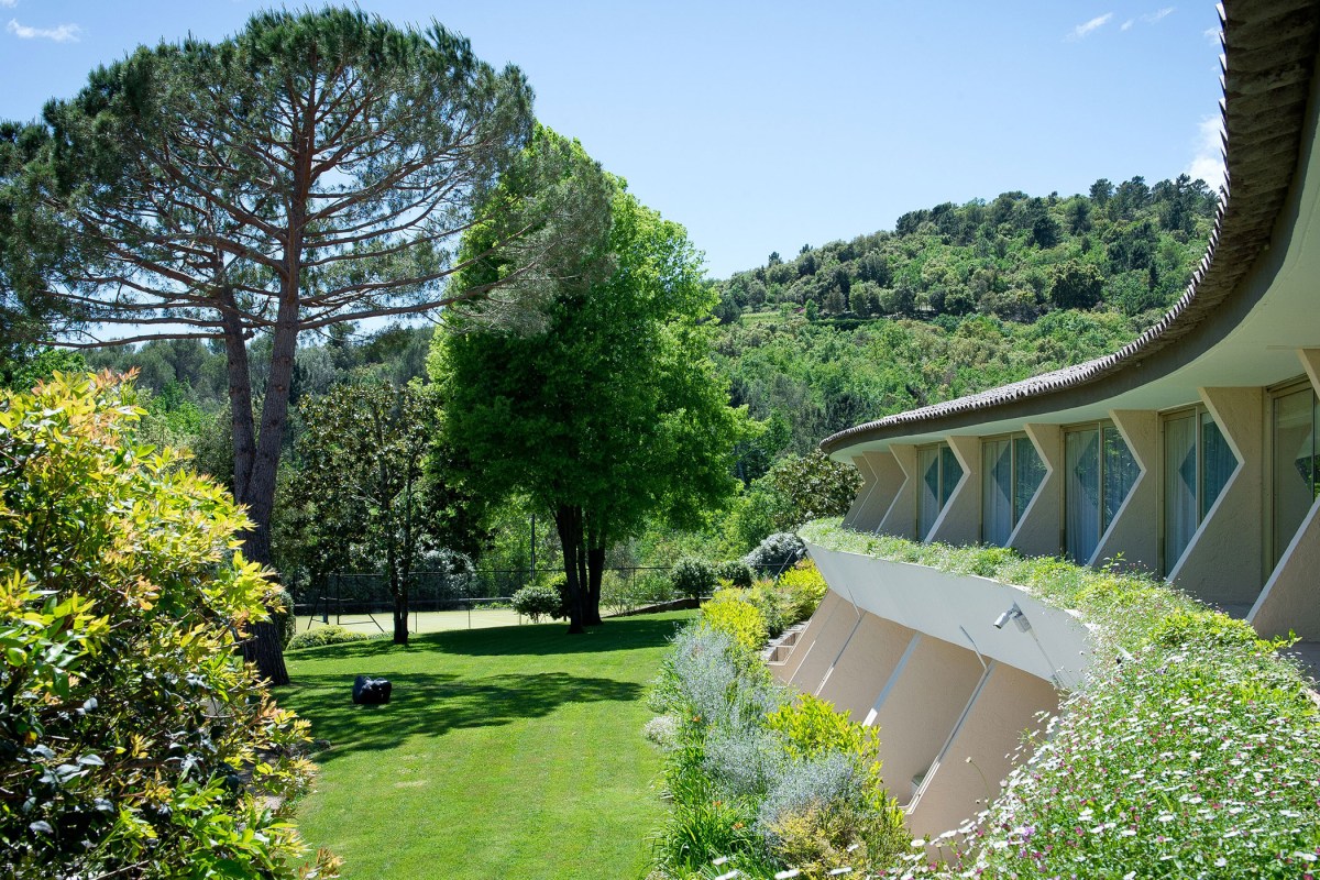 Exterior view of hotel's distinctive curved mid-century building with garden and hills