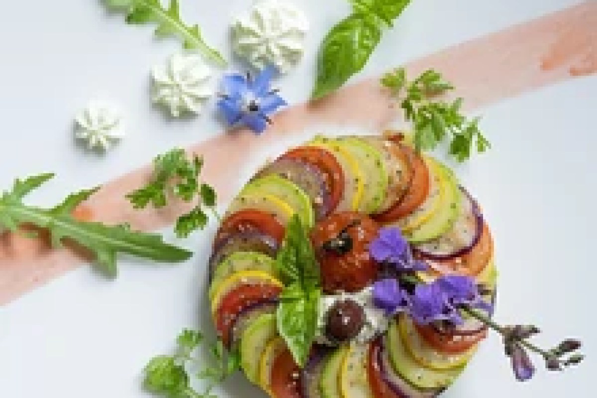 Artfully plated vegetable tian dish with herbs and edible flowers