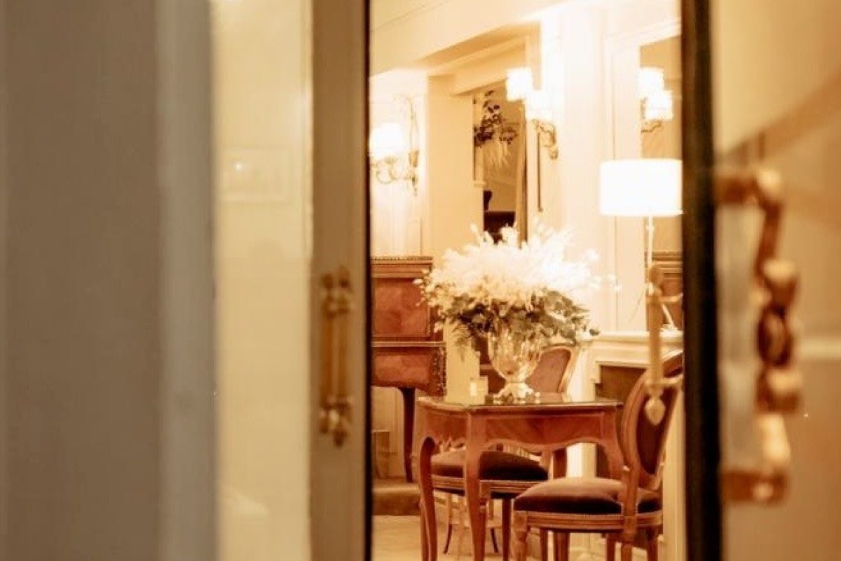 View through open doorway into Lasserre's elegant lobby with antique furniture and flowers