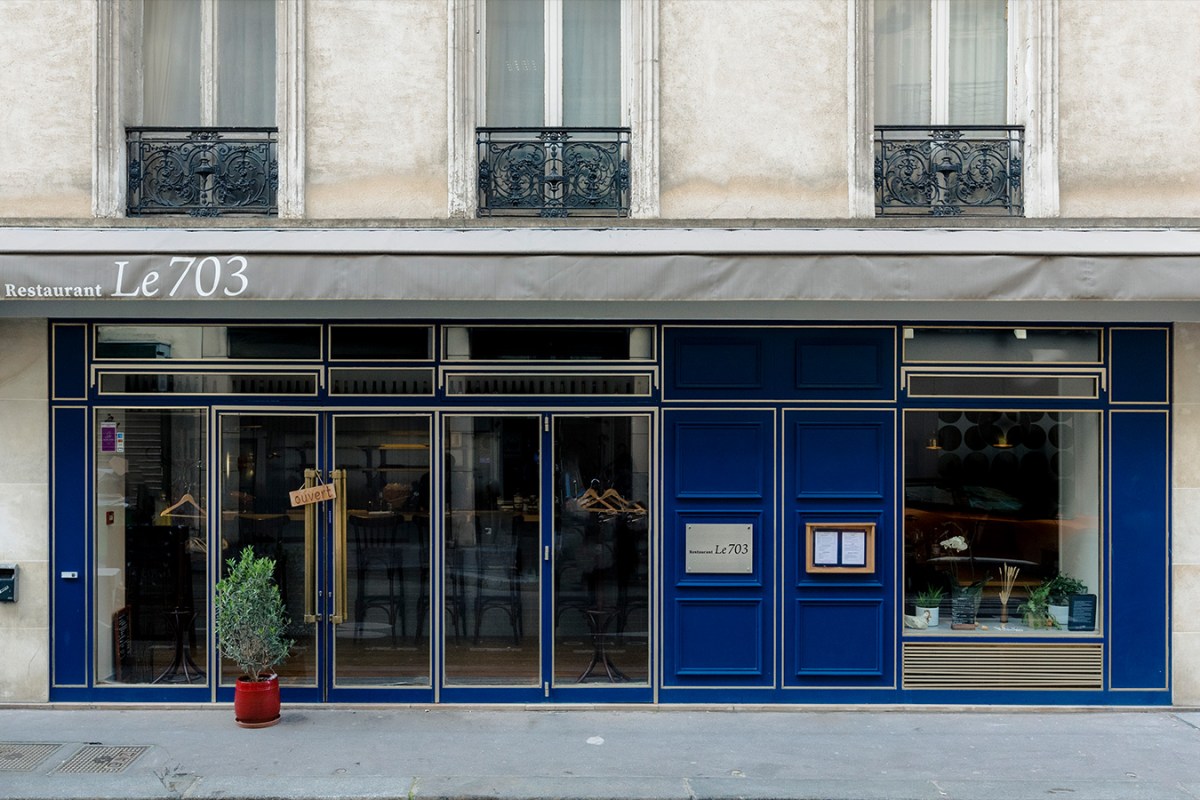 Exterior storefront of Restaurant Le 703 in Paris, blue facade with gold trim and awning