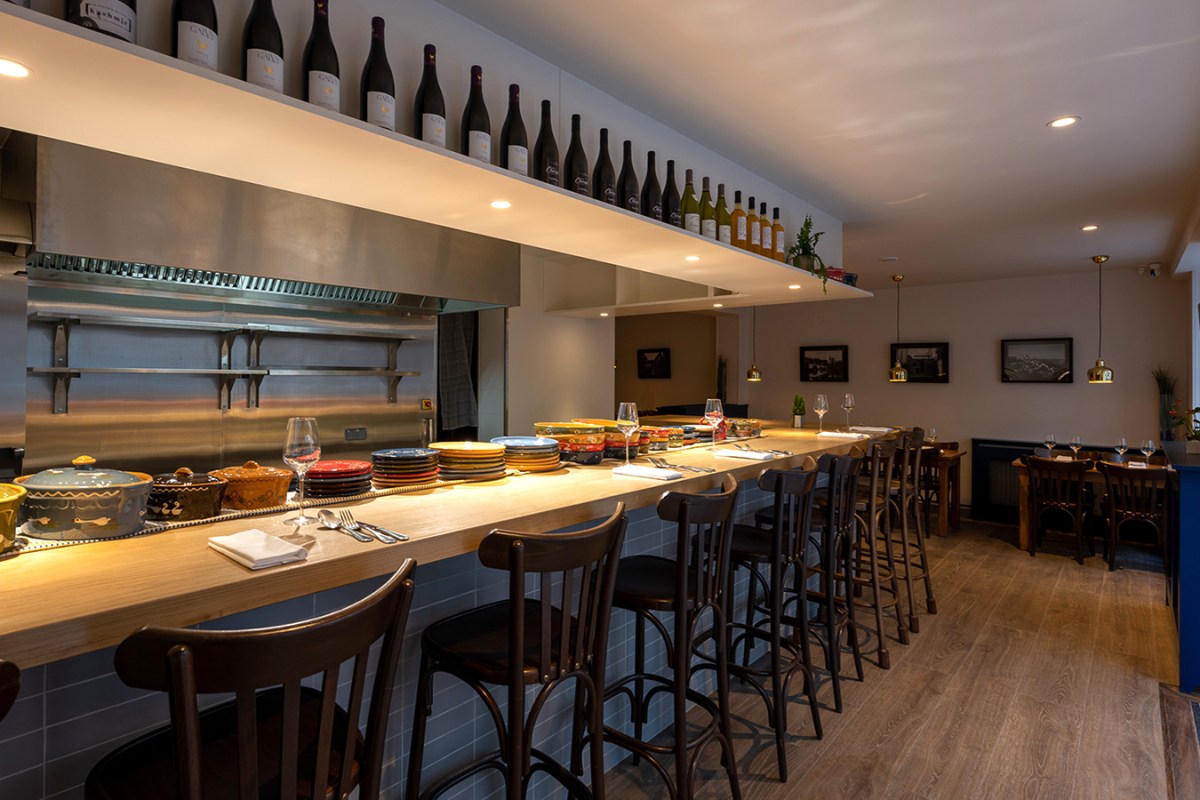 Interior counter seating area of Le 703 with wine bottles, colorful plates and bar stools