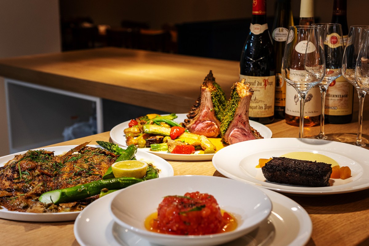 Table spread of dishes at Le 703 including meat, vegetables and tartare with wine glasses